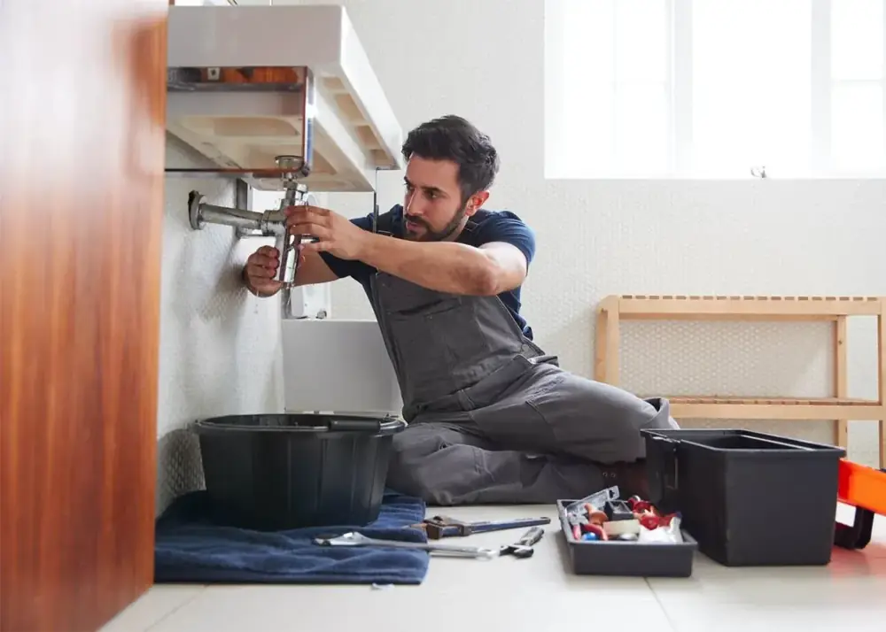 Plumber working on kitchen sink plumbing connections