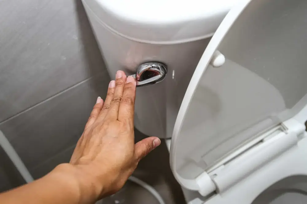 Close-up of toilet tank flush handle during a repair